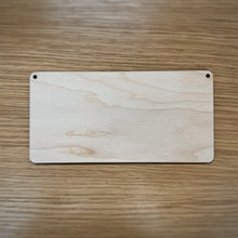 Load image into Gallery viewer, A blank laser cut rectangular plaque with rounded corners and two holes in the top corners, displayed on a wooden surface.
