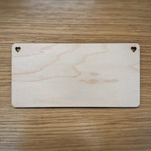 Load image into Gallery viewer, A blank laser cut rectangular plaque with rounded corners and heart shaped holes in the top corners, displayed on a wooden surface.
