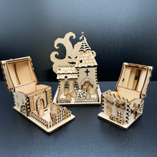 Load image into Gallery viewer, A set of three laser cut models of halloween buildings. A Mausoleum, a church and a house shape. The first and third buildings have their roofs open on the hinge to show that small items like sweets can be stored insde.