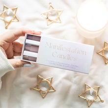 Load image into Gallery viewer, Hand holding a box of 'Manifestation Candles' a spell kit, with star-shaped baubles and a decoration candle jar on a soft surface.