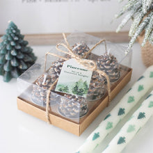 Load image into Gallery viewer, Set of pinecone candles in a clear box with a decorative brown jute bow, surrounded by Christmas decor.