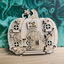Load image into Gallery viewer, A wooden laser cut fairy door shaped like a pumpkin with layered vine leaf detail, four small windows, a working hinged door, and a small engraved sign with the words "Trick or Treat" above the door.