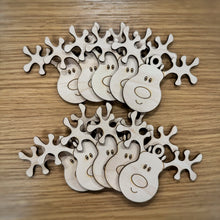 Load image into Gallery viewer, Ten laser cut wooden reindeer tags which could also be tree ornaments. The design is cartoony with two antlers, a big nose and a smiling face. Items on a wooden background.