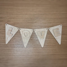 Load image into Gallery viewer, A wooden laser cut triangular shaped bunting, with two holes in the top corners, and rounded corners, plus a cute font layered on top spelling out "LOVE". Item laid out on a darker wooden surface.