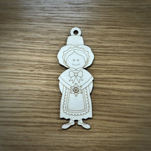 Load image into Gallery viewer, A laser cut wooden tag of a woman in a traditional Welsh outfit. The item has a loop on top of their head. Item on a wooden surface.