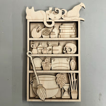 Load image into Gallery viewer, A laser cut kit of a witch's shelf with a Cauldron, Crystal Ball, Books, Vials, Crystals, a skull, wands and other witchy items.