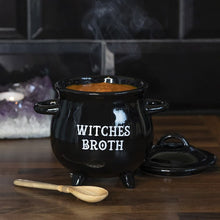 Load image into Gallery viewer, A black ceramic cauldron with 'WITCH'S BROTH' text on the front, accompanied by a wooden spoon, placed on a wooden surface with a blurred background.