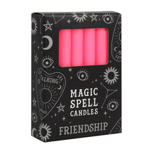 Load image into Gallery viewer, A pack of 12 black Magic Spell Candles in a black cardboard box with a witch themed pattern and the word "Friendship" at the bottom. The pink candles can be seen in a cut out window in the packaging. Item on a white background.