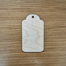 Load image into Gallery viewer, A basic laser cut gift tag shape with a hole at the top on top of a wooden background.
