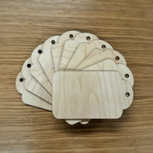 Load image into Gallery viewer, Ten basic laser cut gift tag shapes with a hole at the top, stacked in a pile on top of a wooden background.
