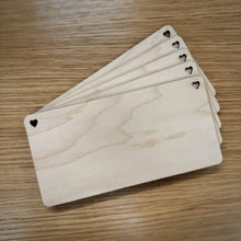 Load image into Gallery viewer, A stack of five blank laser cut rectangular plaques with rounded corners and heart shaped holes in the top corners, displayed on a wooden surface.
