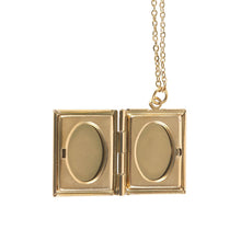 Load image into Gallery viewer, A gold-toned book-shaped pendant necklace. The locket is opened to show the oval windows used to display photos. The gold chain hangs from a ring and loop attached to the locket. Item on a white background.
