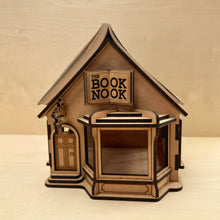 Load image into Gallery viewer, Wooden model of a bookshop engraved with the name &quot;The Book Nook&quot; on the sign, with an open book on top.
