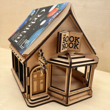 Load image into Gallery viewer, Wooden model of a bookshop engraved with the name &quot;The Book Nook&quot; on the sign, with an open book on top.
