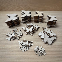 Load image into Gallery viewer, Nine piles or stacks of wooden laser cut blank butterfly shapes in various sizes from 2cm to 10cm. Items laid out on a darker wooden background.

