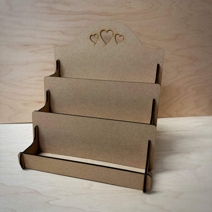 MDF display stand with heart designs cut out on the back board on a wooden background.