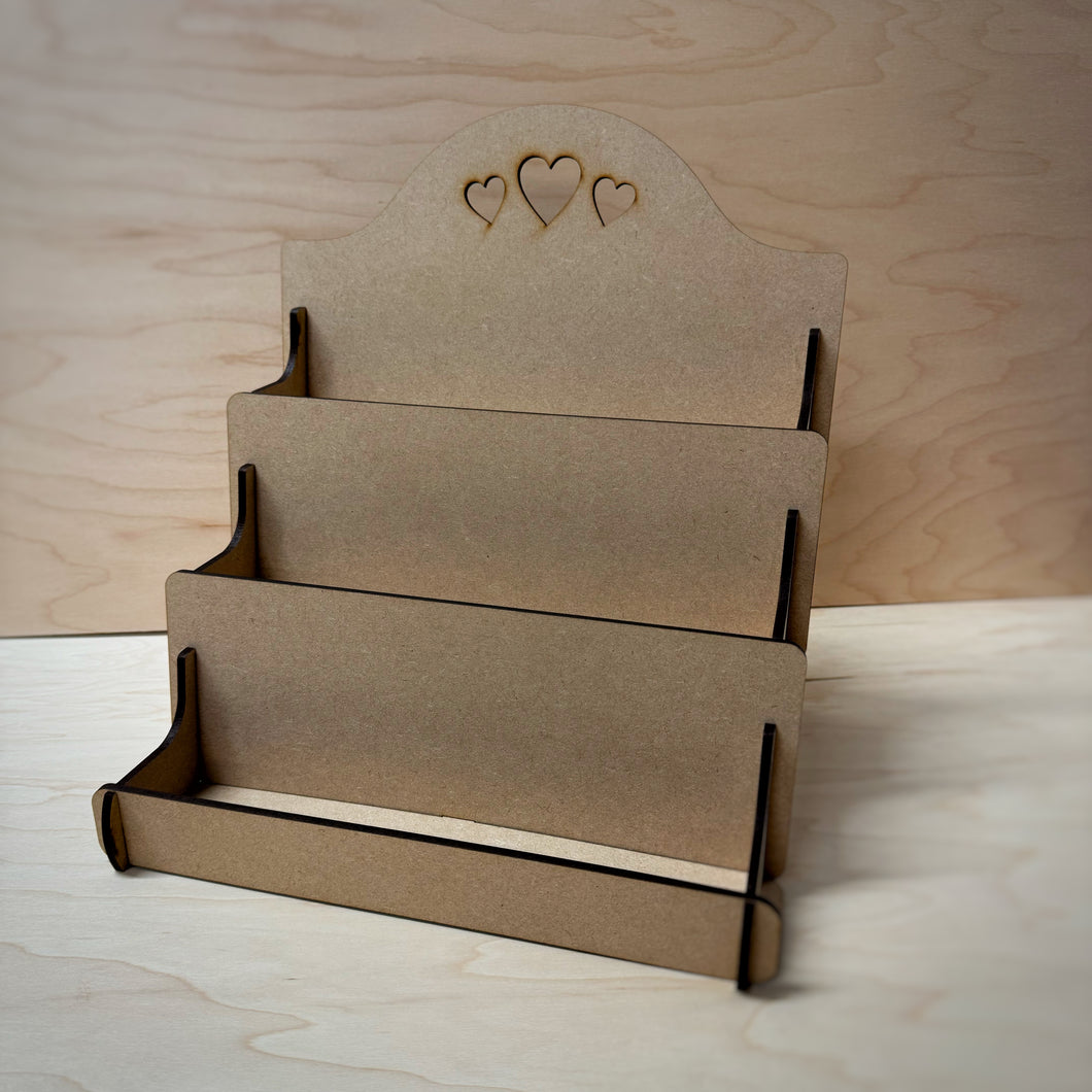 MDF display stand with heart designs cut out on the back board on a wooden background.