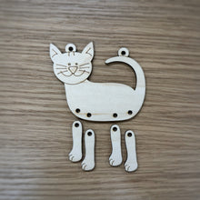 Load image into Gallery viewer, A wooden laser cut cat-shaped ornament with four separate legs so they dangle, shown on a wood-grain background.
