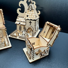 Load image into Gallery viewer, A laser cut halloween house model with its roof open to show that small items like sweets can be stored insde. A halloween church model is behind it.
