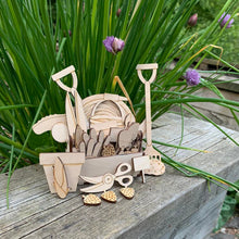 Load image into Gallery viewer, A set of wooden laser cut gardening tools and allotment fruit &amp; vegetables inside a wooden tool box displayed in a garden. 
