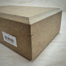 Load image into Gallery viewer, A close up of a rectangular MDF jewellery box to show its bevelled edged lid and a white barcode label, set on a light wood grain surface.
