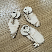 Load image into Gallery viewer, Three laser-cut sets of wooden key &amp; keyring shapes, displayed on a wood grain surface.
