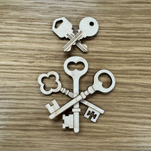 Load image into Gallery viewer, Five laser cut wooden key shapes. Two in a modern style and three in a vintage style arranged on a wooden background.

