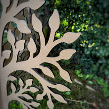 Load image into Gallery viewer, A close-up of an MDF laser cut free standing tree with leafy branch patterns, set against a blurred green garden background.
