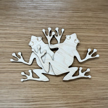 Load image into Gallery viewer, Two wooden laser cut frog shapes stacked on top of each other placed on a wood surface.
