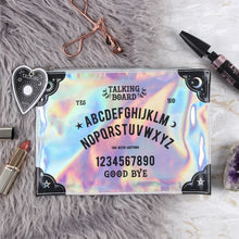 Load image into Gallery viewer, An iridescent makeup pouch with a spirit board design and a planchette zipper tag, displayed on a faux fur surface alongside example beauty accessories.

