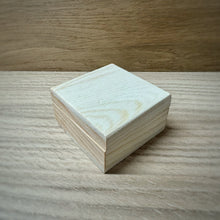 Load image into Gallery viewer, A small blank wooden box with a hinged lid, made from pine wood, shown on a darker wooden surface.
