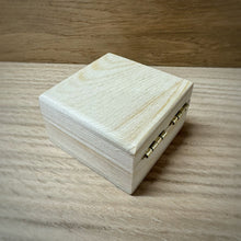 Load image into Gallery viewer, The back and top of a small blank wooden box with a hinged lid and brass hinges. Made from pine wood, shown on a darker wooden surface.
