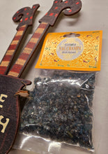 Load image into Gallery viewer, A bag of Nag Champa Resin with an ornate orange label. The packet is next to a cut out of a pair of witch's legs sticking out of a couldren for display.
