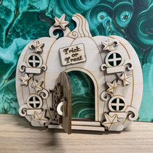 Load image into Gallery viewer, A wooden laser cut fairy door shaped like a pumpkin with layered vine leaf detail, four small windows, a working hinged door, and a small engraved sign with the words "Trick or Treat" above the door.

