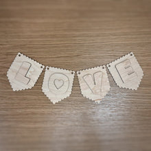 Load image into Gallery viewer, A wooden laser cut scalloped pennant shaped bunting, with a cute font layered on top spelling out "LOVE". Item laid out on a darker wooden surface.
