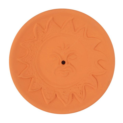 A terracotta incense stick holder plate with an embossed sun and face design.