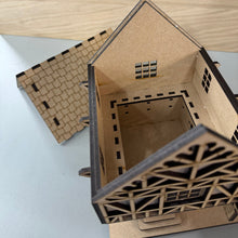 Load image into Gallery viewer, A 3D MDF laser cut Tudor Tavern with it's roof lid removed to see the hollow centre for storage. The roof is behind the house and the mock beams can be seen on the front.
