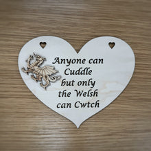 Load image into Gallery viewer, A laser cut heart shaped plaque with the phrase "Anyone can Cuddle but only the Welsh can Cwtch" cut out of the heart and a layered, unattached Welsh Dragon shape to glue onto the plaque. Items on a wooden background.
