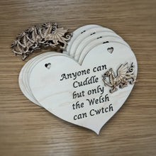 Load image into Gallery viewer, Five laser cut heart shaped plaques with the phrase "Anyone can Cuddle but only the Welsh can Cwtch" cut out of the hearts and five layered, unattached Welsh Dragon shapes to glue onto the plaques. Items on a wooden background.
