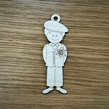 Load image into Gallery viewer, A laser cut wooden tag of a man in a traditional Welsh outfit. The item has a loop on top of their head. Item on a wooden surface. 
