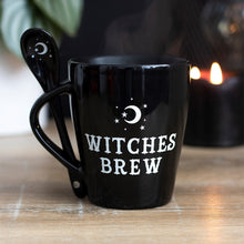 Load image into Gallery viewer, Black mug with 'Witches Brew' text on a wooden surface with a candle in the background
