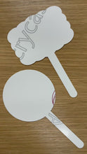 Load and play video in Gallery viewer, Two white laser cut acrylic signs with handles, one rectangular scalloped shaped and one circle shaped sign, placed on a wooden surface. Both signs have their protective film removed in the video to show the white acrylic. 
