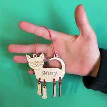 Load image into Gallery viewer, A hand holding a hanging wooden cat decoration with red thread and the name 'Misty' engraved on it.

