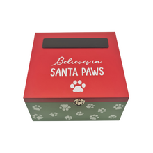 Load image into Gallery viewer, A Christmas themed box for pets. It features a green box with a white paw print pattern and a red lid. On the top of the box there is a black chalkboard panel to write in your pet's name and below that is a white paw and the words "Believes in Santa Paws". There's a gold clasp on the front and the lid is hinged. Item on a white background.
