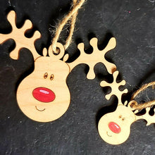 Load image into Gallery viewer, Two laser cut wooden reindeer shapes in two sizes. Their noses are painted red and each has a jute string for hanging. Items on a black slate background.
