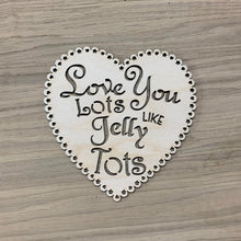 Load image into Gallery viewer, A wooden laser cut scalloped heart with tiny alternating hearts and stars cut out of each scallop bump. The phrase "Love You Lots Like Jelly Tots" is cut out in various types of font in the centre of the heart plaque.
