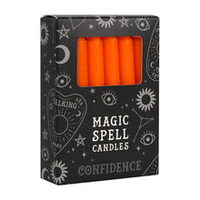 Load image into Gallery viewer, A pack of 12 black Magic Spell Candles in a black cardboard box with a witch themed pattern and the word "Confidence" at the bottom. The orange candles can be seen in a cut out window in the packaging. Item on a white background.
