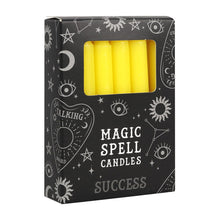 Load image into Gallery viewer, A pack of 12 black Magic Spell Candles in a black cardboard box with a witch themed pattern and the word "Success" at the bottom. The yellow candles can be seen in a cut out window in the packaging. Item on a white background.

